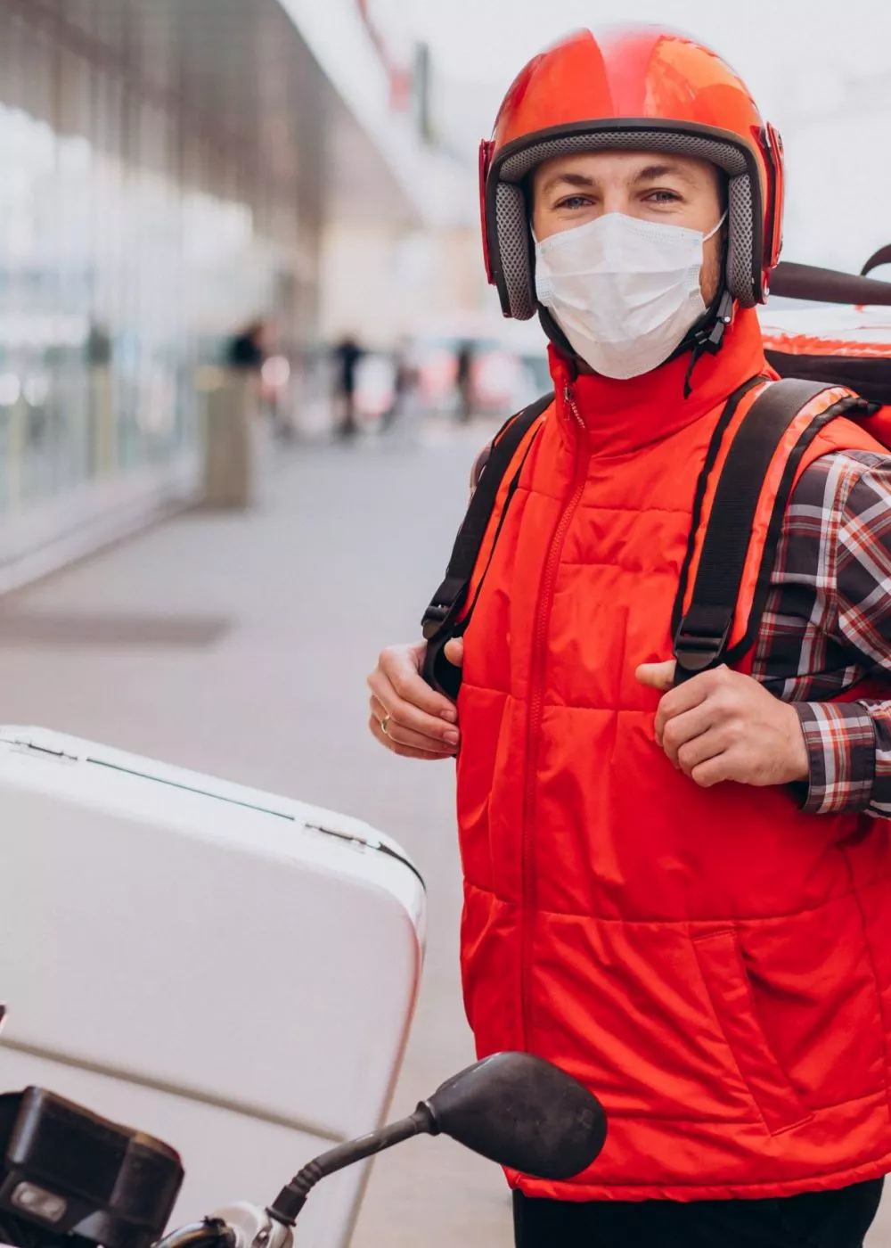 Food delivery boy driving scooter with box with food and wearing mask Food delivery boy driving scooter with box with food and wearing mask
